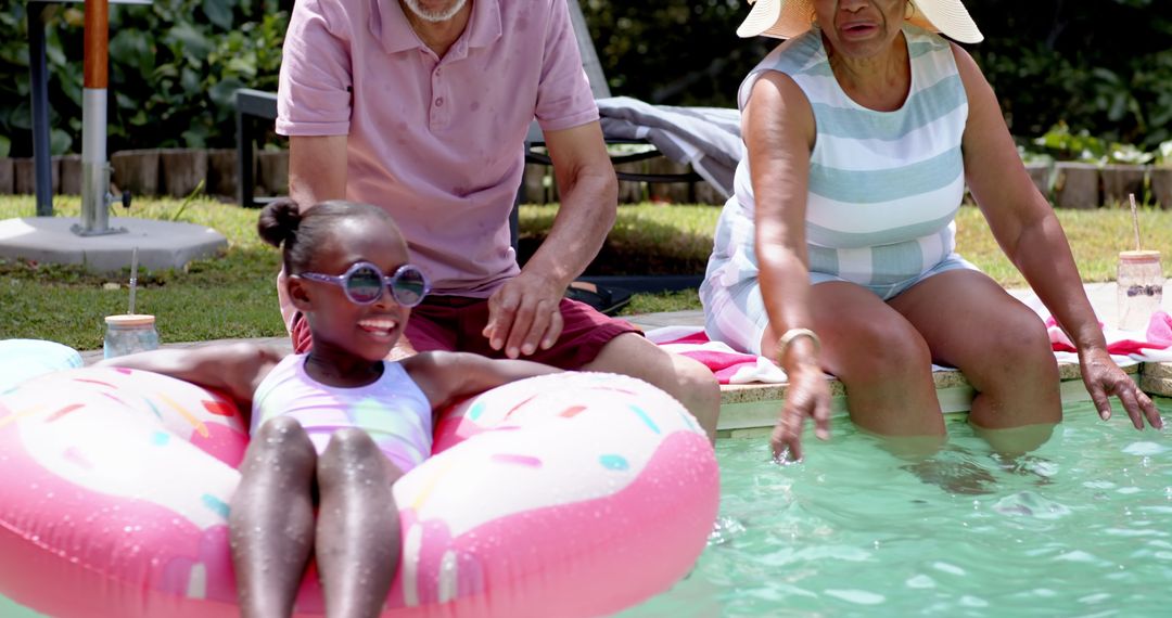 Elderly Couple Enjoying Summer with Granddaughter in Pool