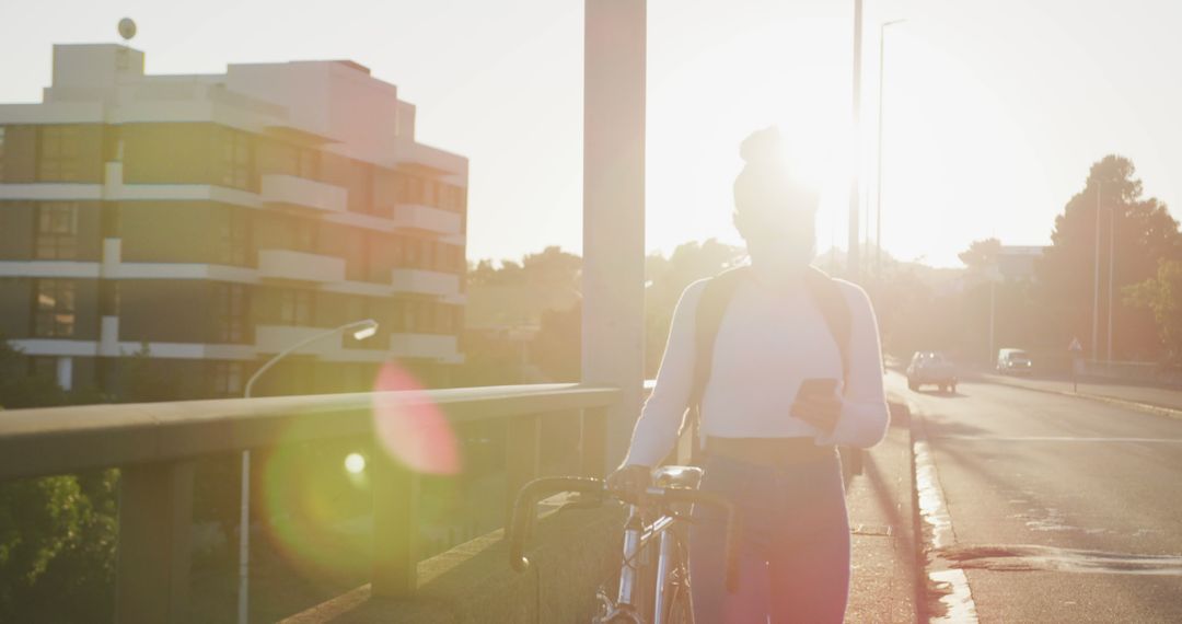 Woman Walking with Bicycle on Sunny Urban Road at Sunset - Free Images, Stock Photos and Pictures on Pikwizard.com