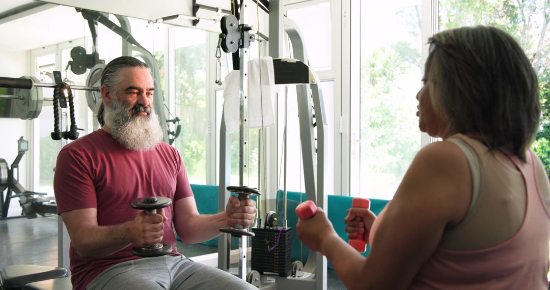 Senior Couple Exercising With Dumbbells in Bright Gym