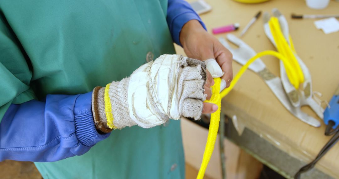 Worker Handling Rope with Protective Gloves in Workshop - Free Images, Stock Photos and Pictures on Pikwizard.com