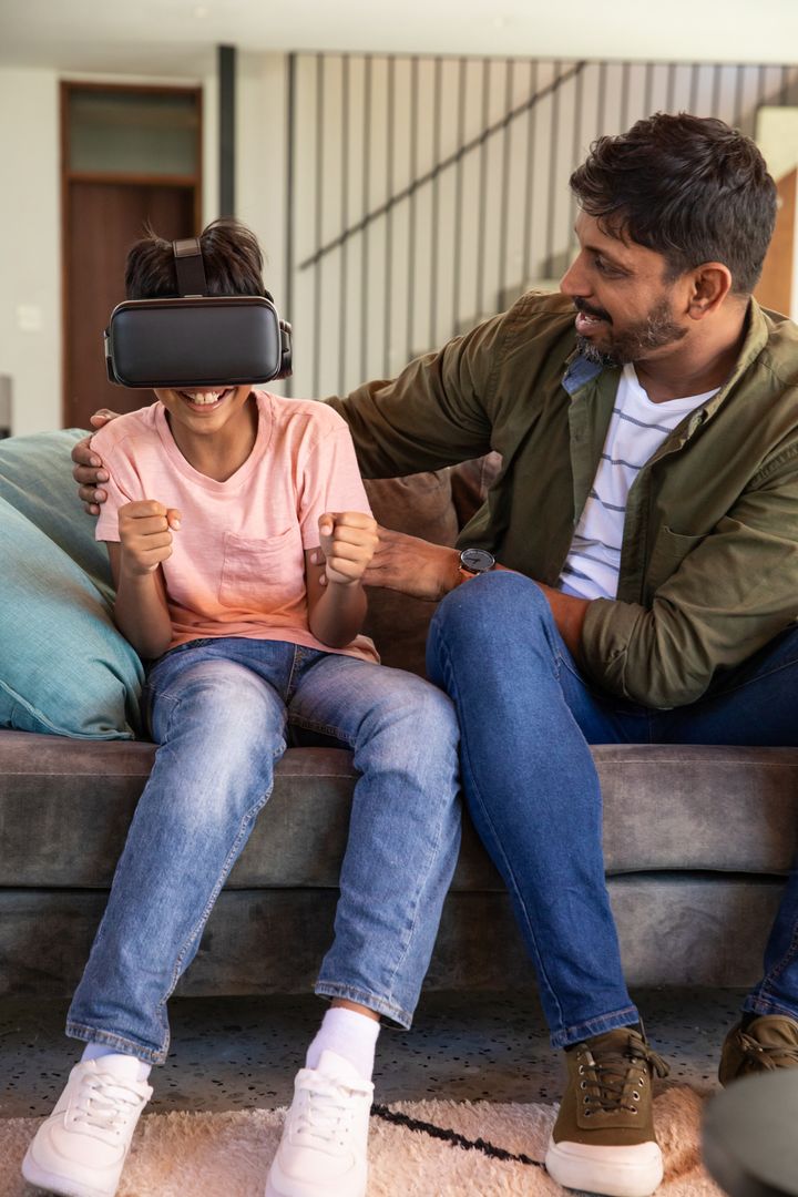 Father and Son Enjoying Virtual Reality at Home in Living Room