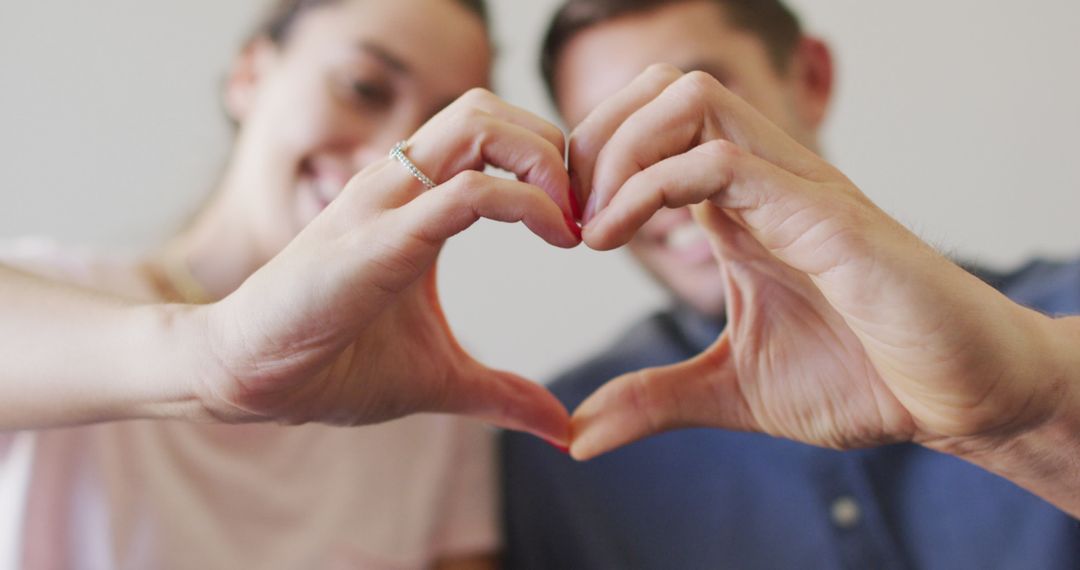 Happy Couple Forming Heart Shape with Hands