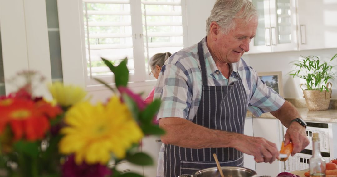 Elderly Man Cooking in Modern Kitchen with Fresh Flowers - Free Images, Stock Photos and Pictures on Pikwizard.com