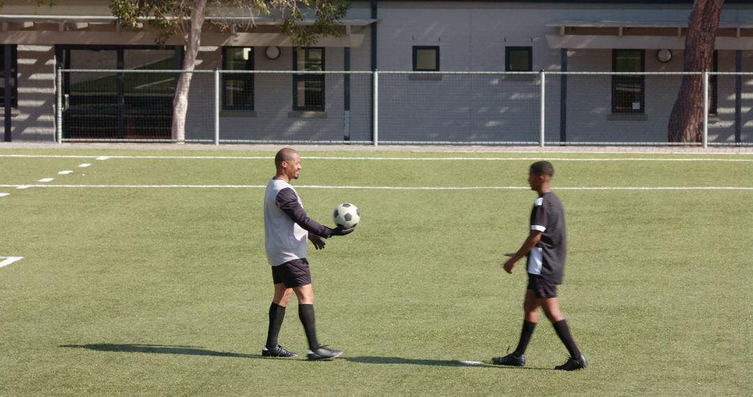 Young Soccer Player Practicing with Coach on School Field
