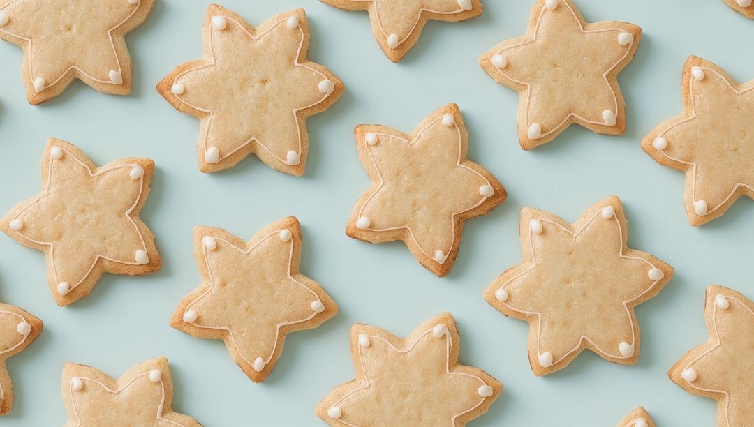 Arranging star-shaped shortbread cookies on pastel blue background with white icing dots