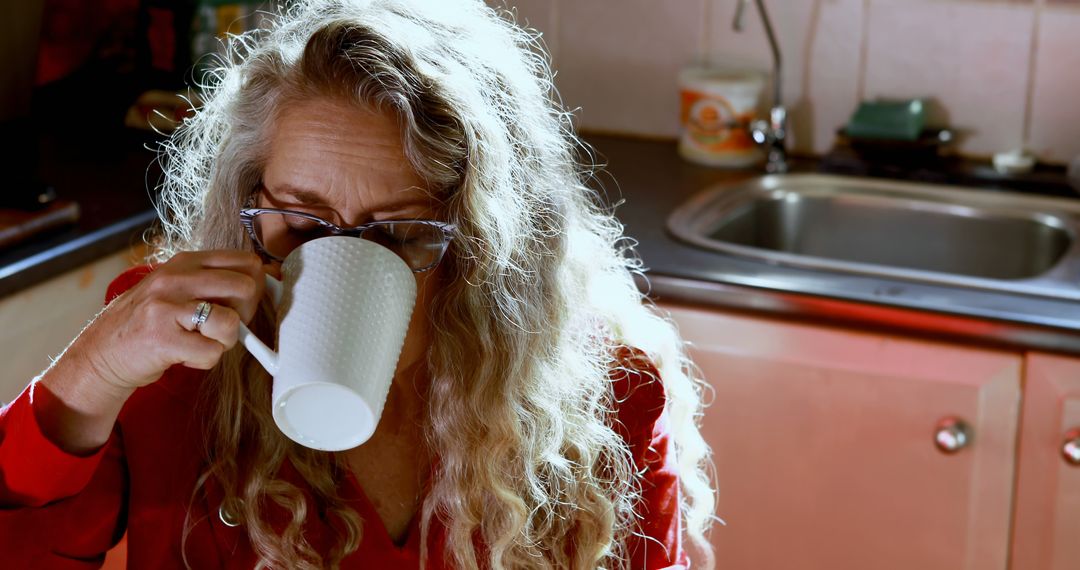 Mature Woman with Long Curly Hair Drinking Coffee in Kitchen - Free Images, Stock Photos and Pictures on Pikwizard.com