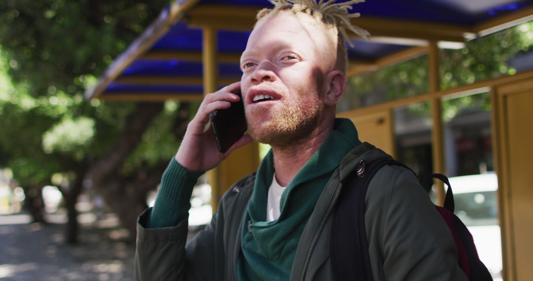 Young Albino Man Talking on Phone Outdoors at Bus Stop - Free Images, Stock Photos and Pictures on Pikwizard.com