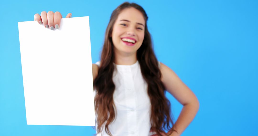 Smiling Woman Holding Blank White Sheet on Blue Background - Free Images, Stock Photos and Pictures on Pikwizard.com