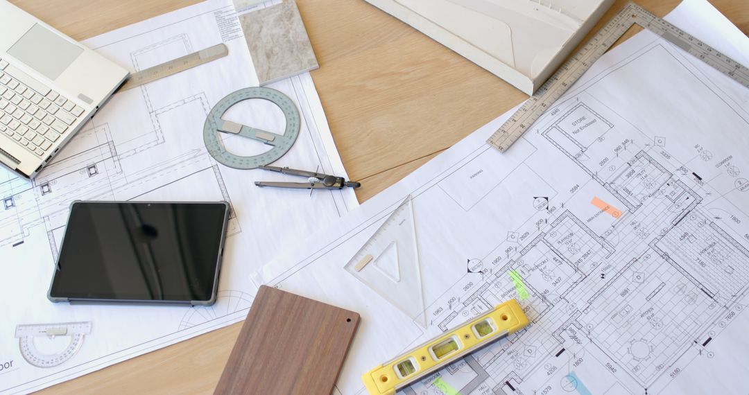 Architectural Blueprints with Construction Tools on Office Desk