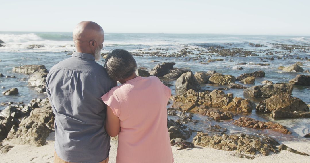 Senior couple embracing standing on rocky beach - Free Images, Stock Photos and Pictures on Pikwizard.com