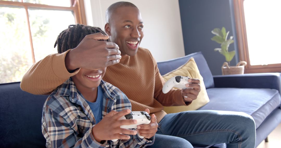 Joyful African American Father and Son Playing Video Games on Couch - Free Images, Stock Photos and Pictures on Pikwizard.com