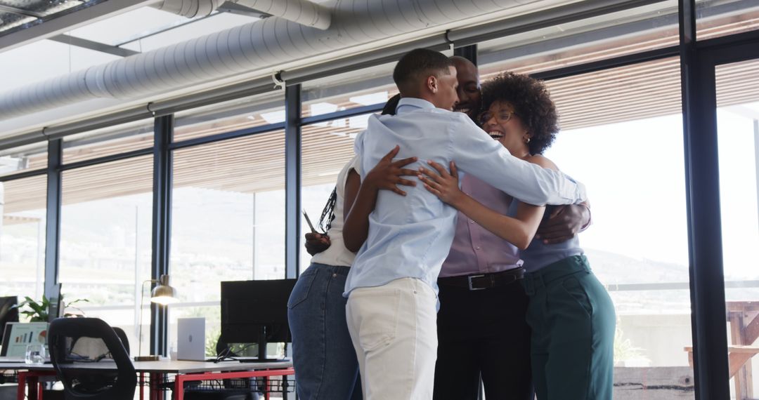 Diverse Team Hugging and Celebrating Success in Modern Office