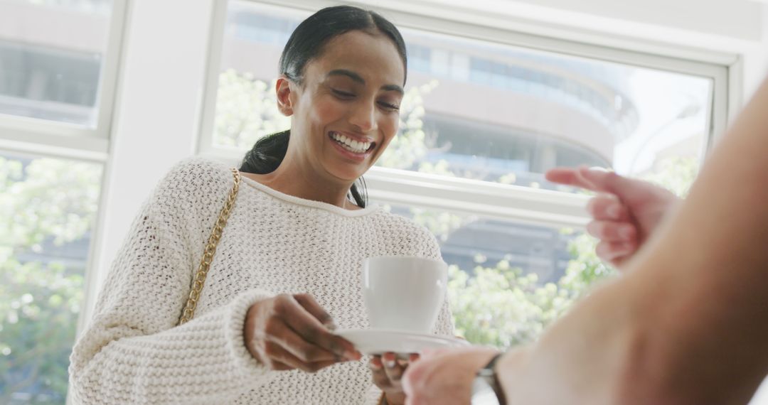 Smiling woman in casual attire holding coffee cup in bright environment - Free Images, Stock Photos and Pictures on Pikwizard.com