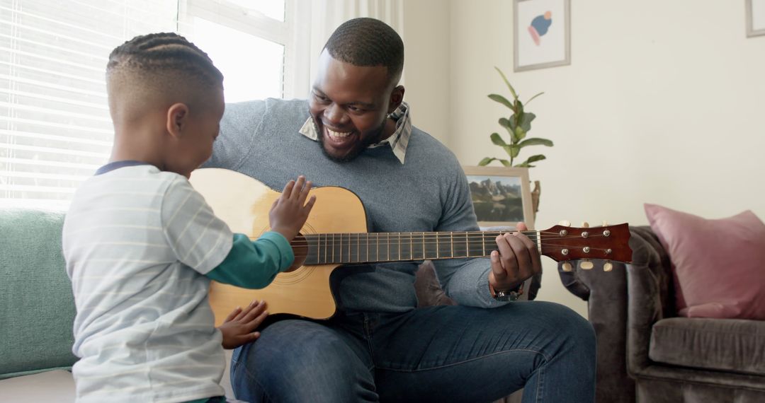 Happy Father and Son Playing Guitar Together at Home - Free Images, Stock Photos and Pictures on Pikwizard.com