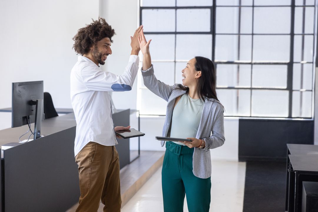 Diversified Team High-Fiving in Modern Open-Plan Office Environment