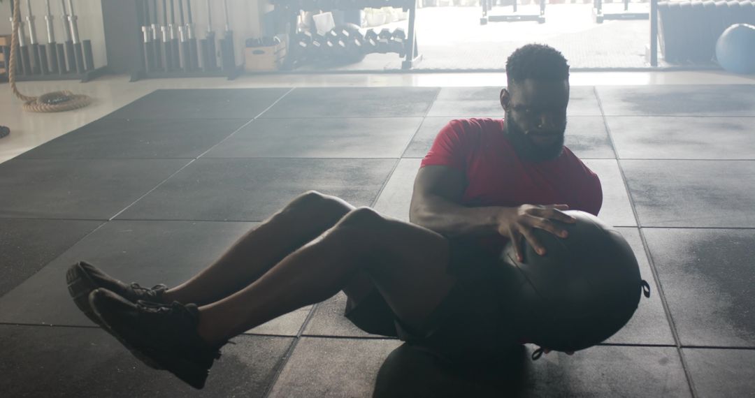 Man Working Out with Medicine Ball in Sunlit Gym Setting