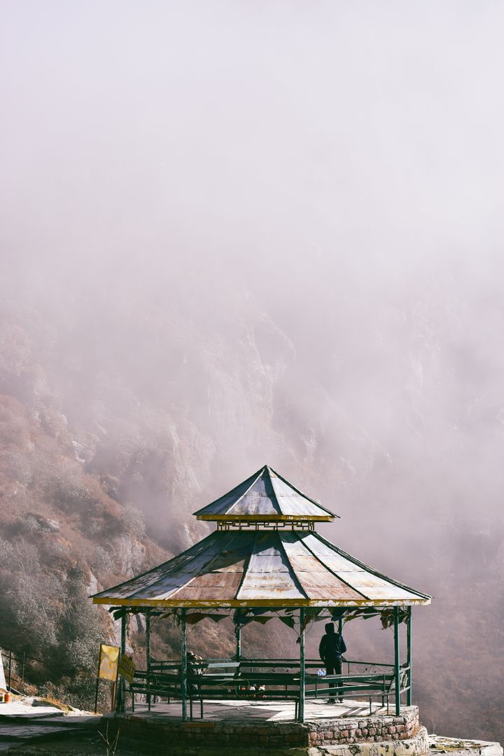 Person Standing in Rustic Gazebo Overlooking Misty Mountain - Free Images, Stock Photos and Pictures on Pikwizard.com
