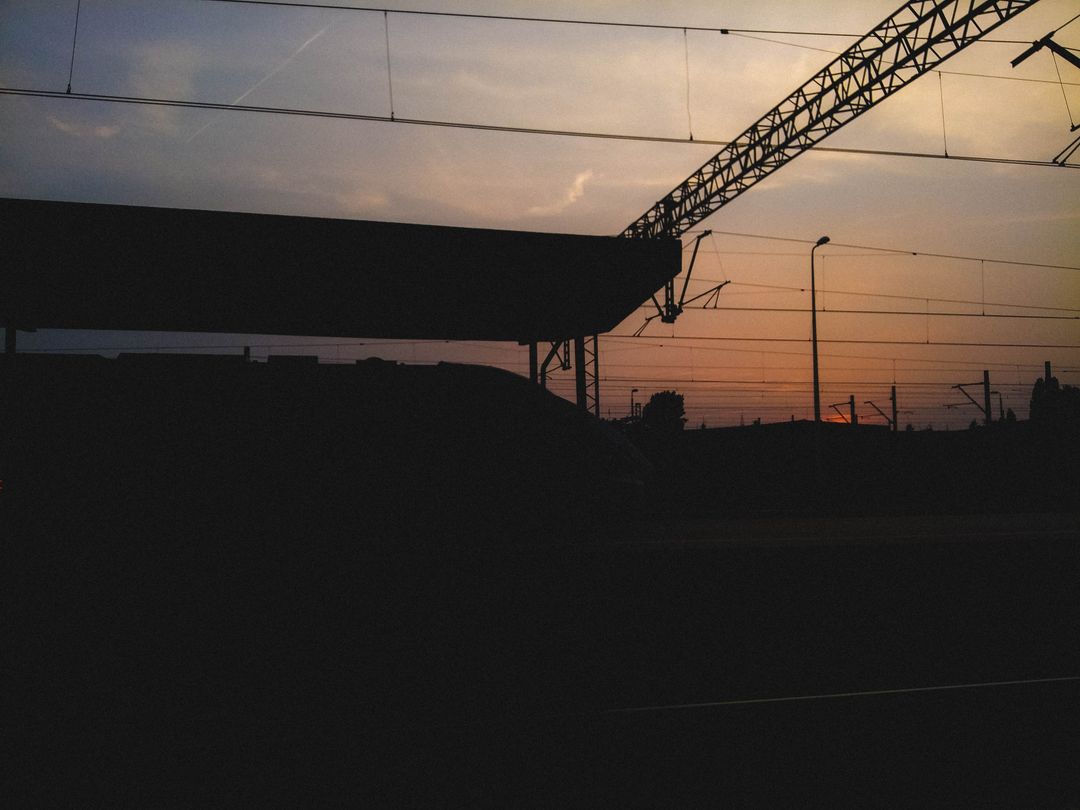 Sunset Silhouette of Train Station with Overhead Lines - Free Images, Stock Photos and Pictures on Pikwizard.com