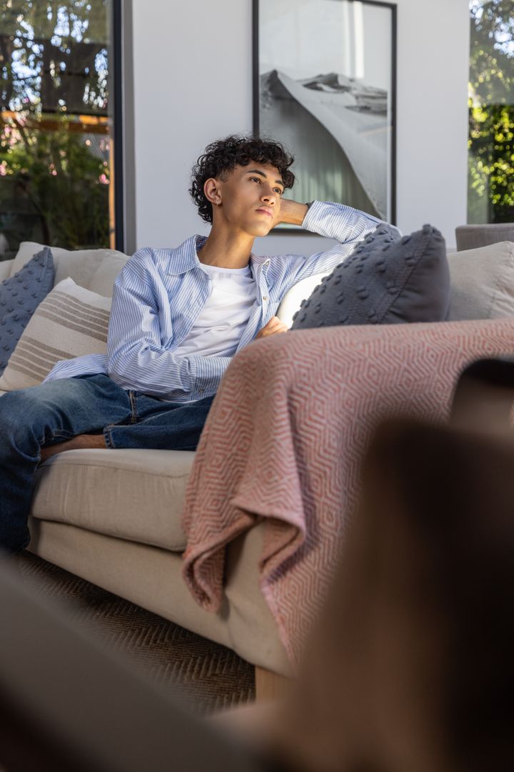 Young Man Relaxing on Sofa Enjoying Sunlit Modern Home