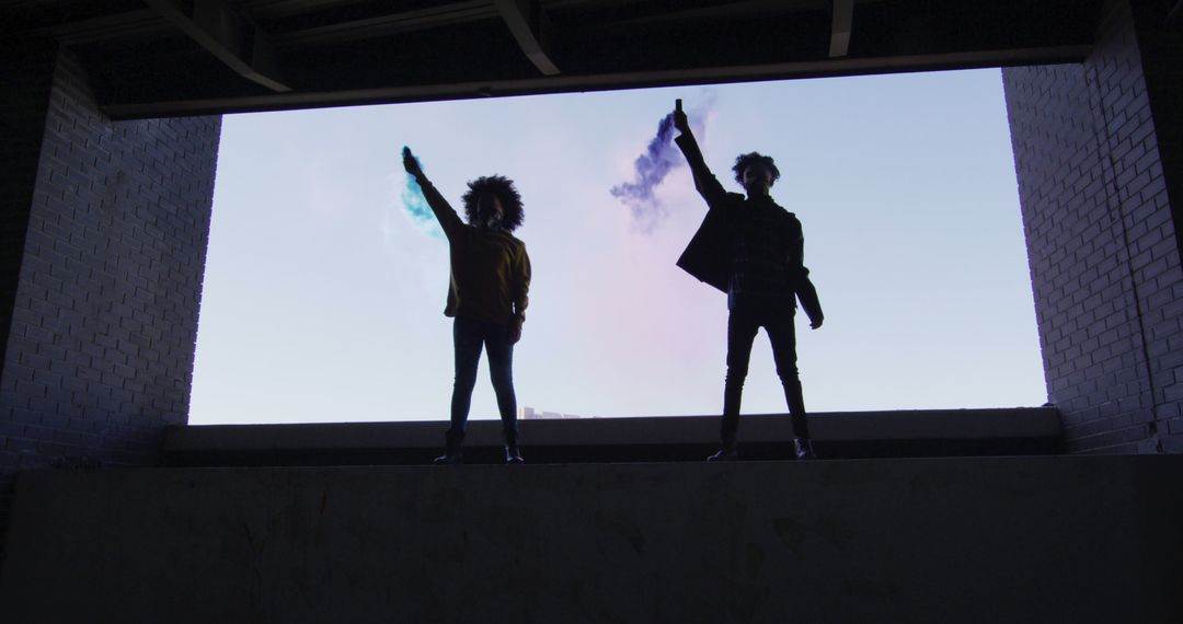 Silhouettes of Two Young Individuals Holding Smoke Flares in Urban Location - Free Images, Stock Photos and Pictures on Pikwizard.com