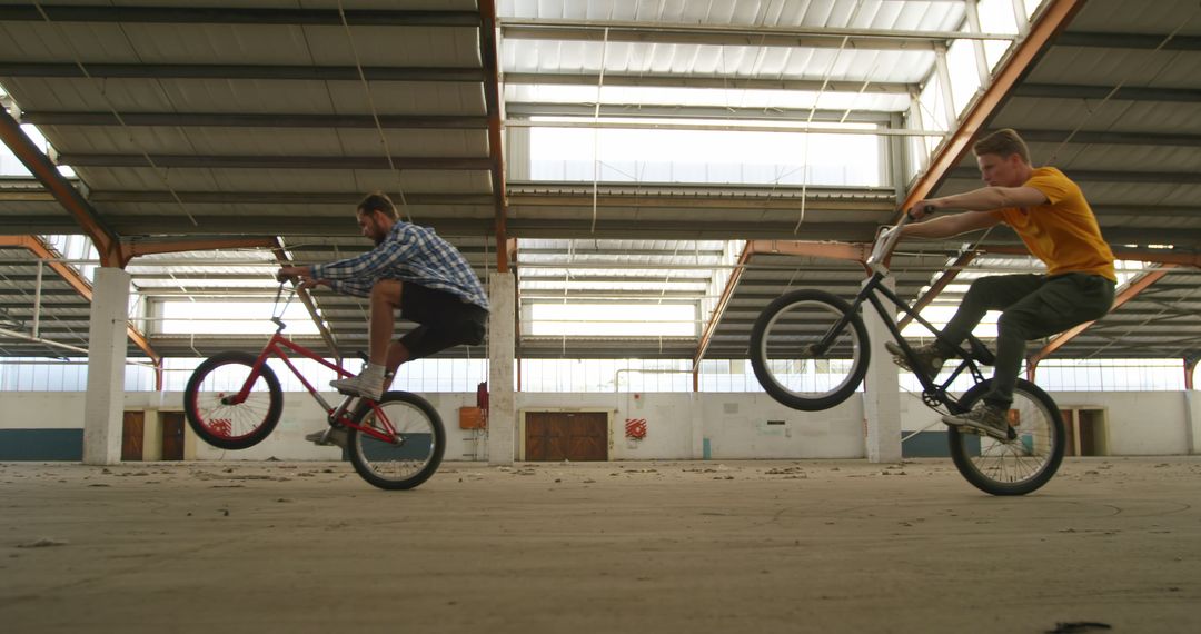 Young Men Perform BMX Tricks in Empty Warehouse - Free Images, Stock Photos and Pictures on Pikwizard.com