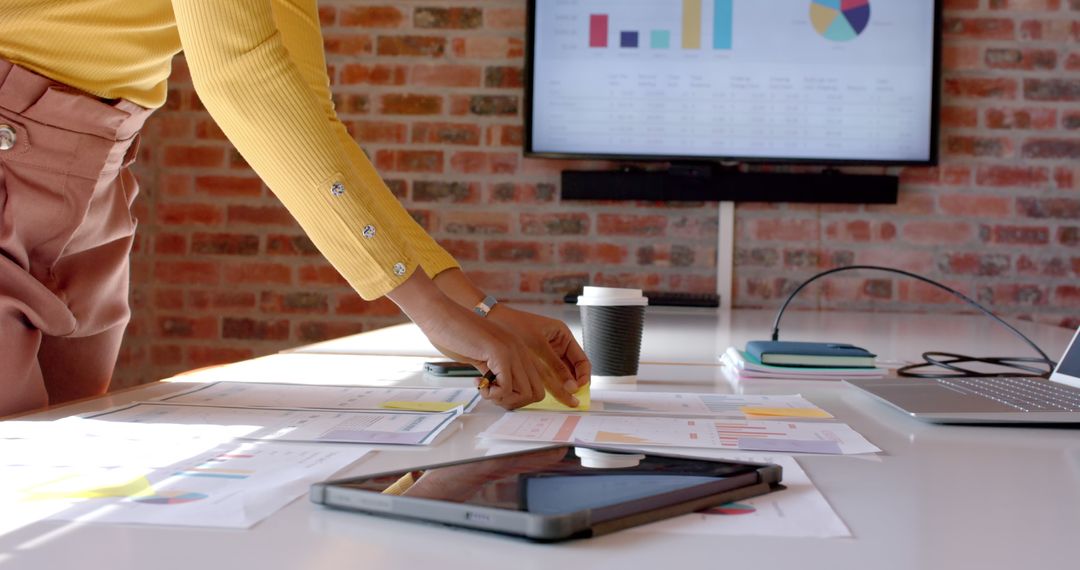 Person Organizing Documents in Modern Office with Charts on Screen - Free Images, Stock Photos and Pictures on Pikwizard.com