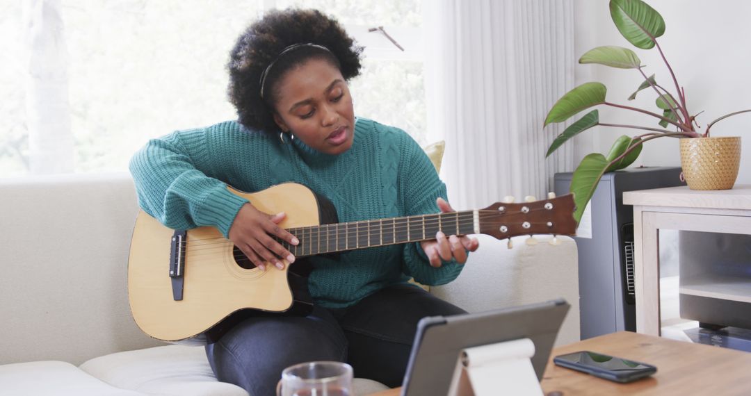 Woman Playing Acoustic Guitar While Watching Tutorial on Tablet - Free Images, Stock Photos and Pictures on Pikwizard.com