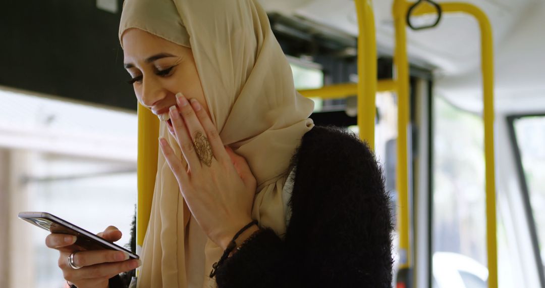 Smiling Woman in Hijab Using Smartphone on Public Bus - Free Images, Stock Photos and Pictures on Pikwizard.com