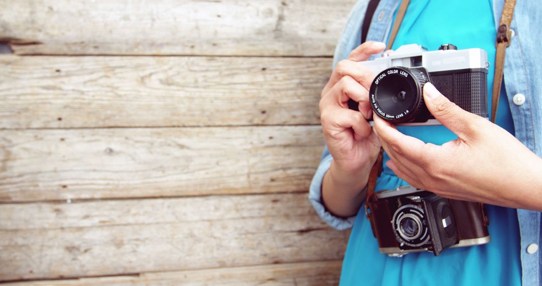 A person is adjusting the settings on a vintage camera, with copy space on the wooden background - Free Images, Stock Photos and Pictures on Pikwizard.com