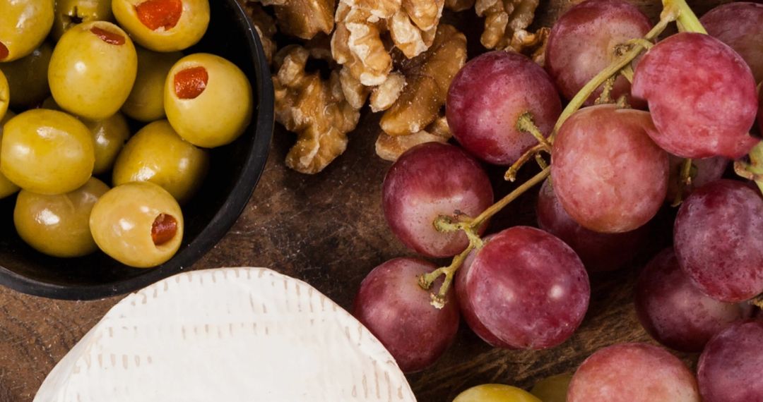 Rustic Cheese Platter with Grapes, Olives, and Walnuts on Wooden Table