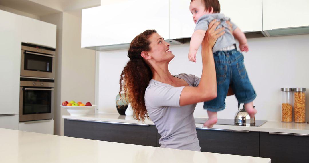 Mother Lifting Baby in Modern Kitchen - Free Images, Stock Photos and Pictures on Pikwizard.com