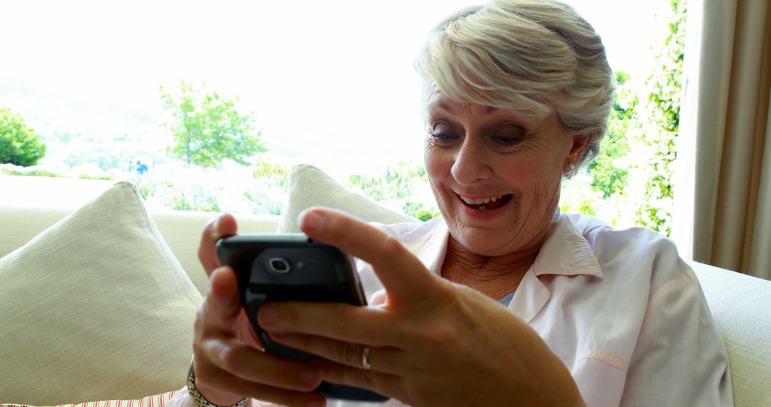 Elderly Woman Smiling While Using Smartphone at Home - Free Images, Stock Photos and Pictures on Pikwizard.com