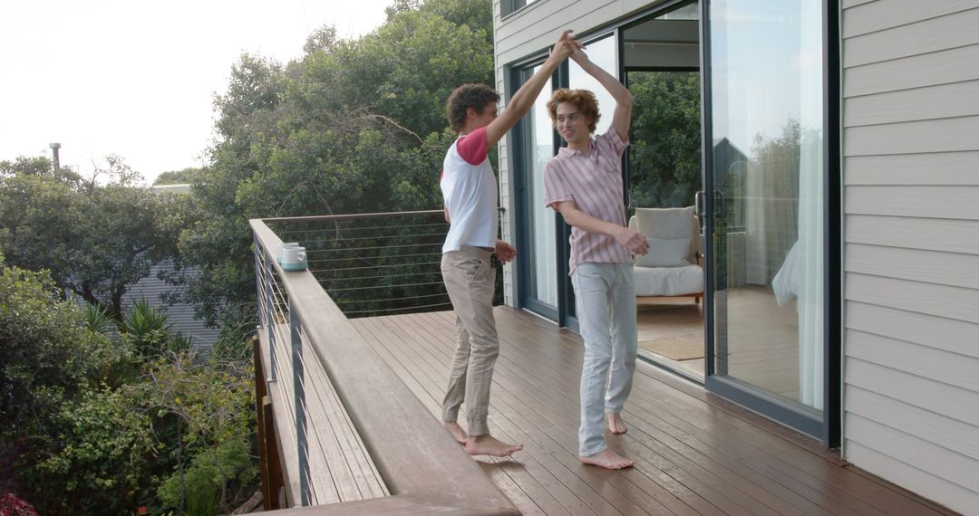 Joyful Same-Sex Couple Dancing on Sunlit Balcony