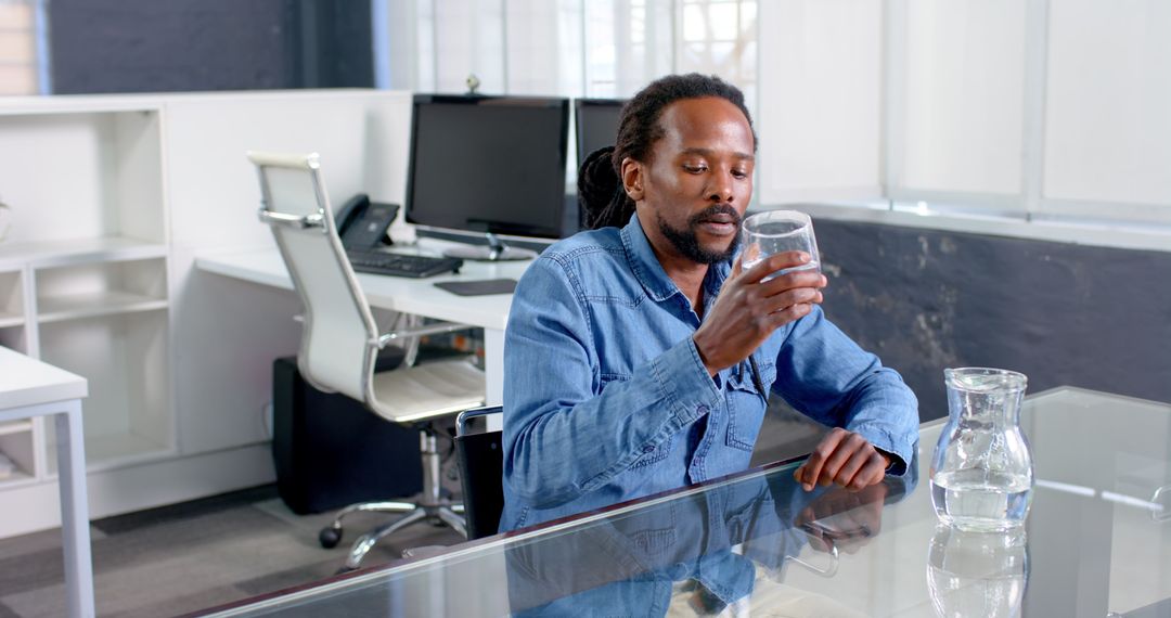 Man Evualating Glass of Water in Office Environment