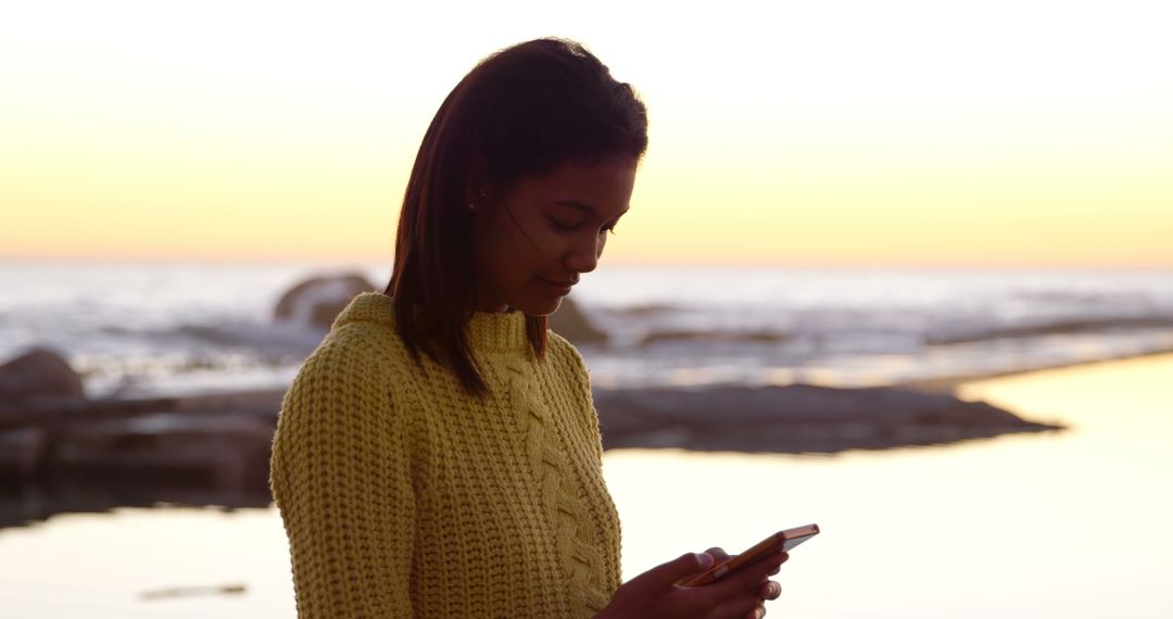 Woman Using Smartphone by Seaside at Sunset - Free Images, Stock Photos and Pictures on Pikwizard.com