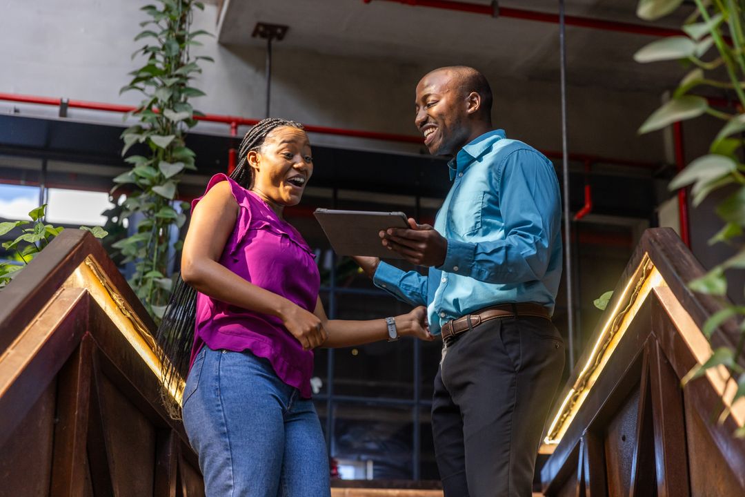 Smiling Coworkers Collaborate with Tablet on Urban Staircase