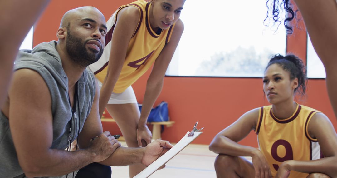 Basketball coach discussing strategy with female players on indoor court - Free Images, Stock Photos and Pictures on Pikwizard.com