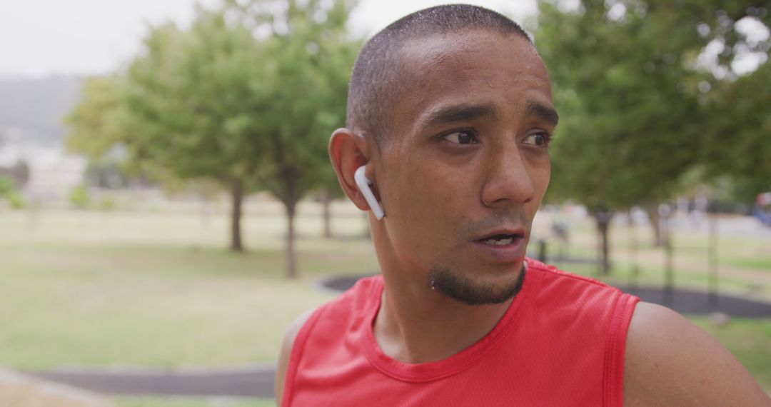 Determined Athlete Wearing Red Tank Top and Earbuds During Outdoor Workout - Free Images, Stock Photos and Pictures on Pikwizard.com