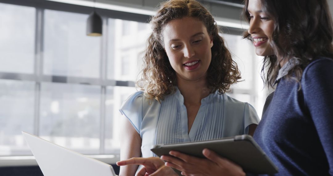 Diverse Female Colleagues Using Tablets in Office Meeting