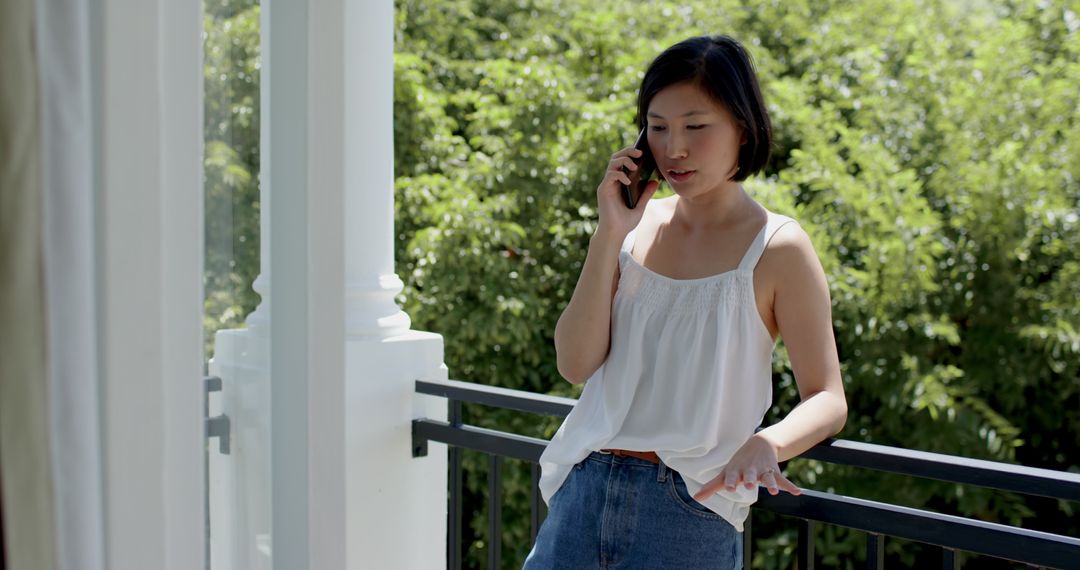 Woman Enjoys Sunny Day on Balcony While Talking on Smartphone