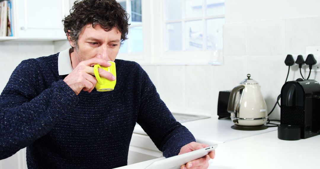 Man Drinking Coffee and Using Tablet in Modern Kitchen - Free Images, Stock Photos and Pictures on Pikwizard.com