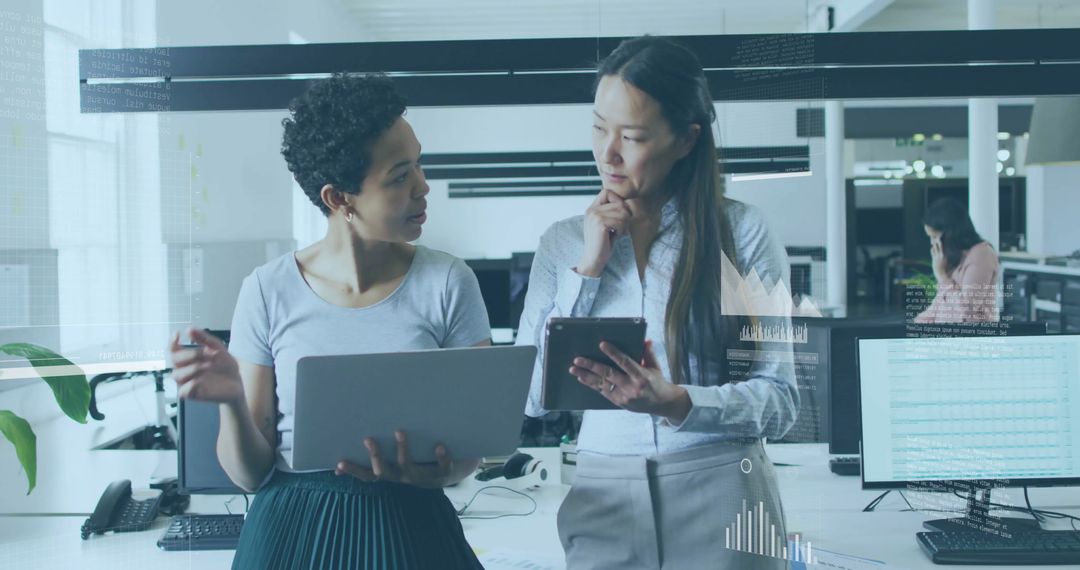 Two Businesswomen Collaborating Over Data and Technology in Modern Office