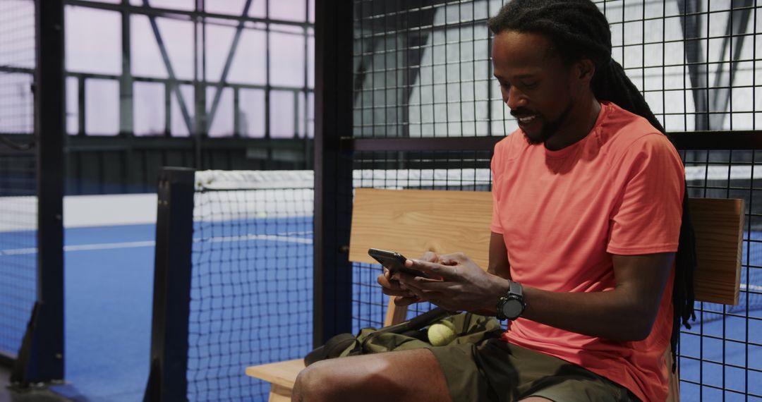 Man Relaxing on Bench Checking Smartphone Near Padel Court