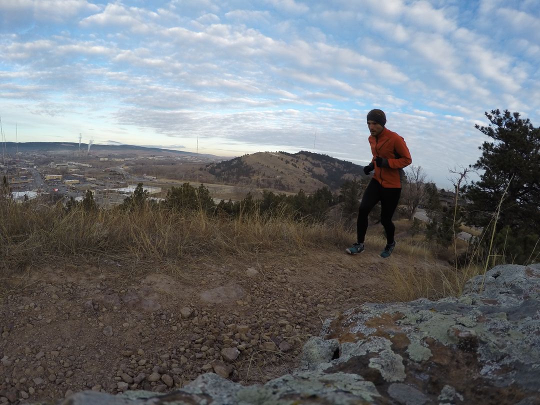 Male Runner in Orange Jacket Jogging on Rocky Hill Trail at Sunrise - Free Images, Stock Photos and Pictures on Pikwizard.com