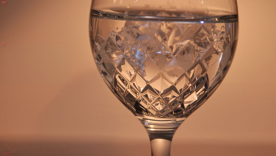 Cut Crystal Goblet Reflecting Warm Amber Light with Faceted Pattern and Water Line