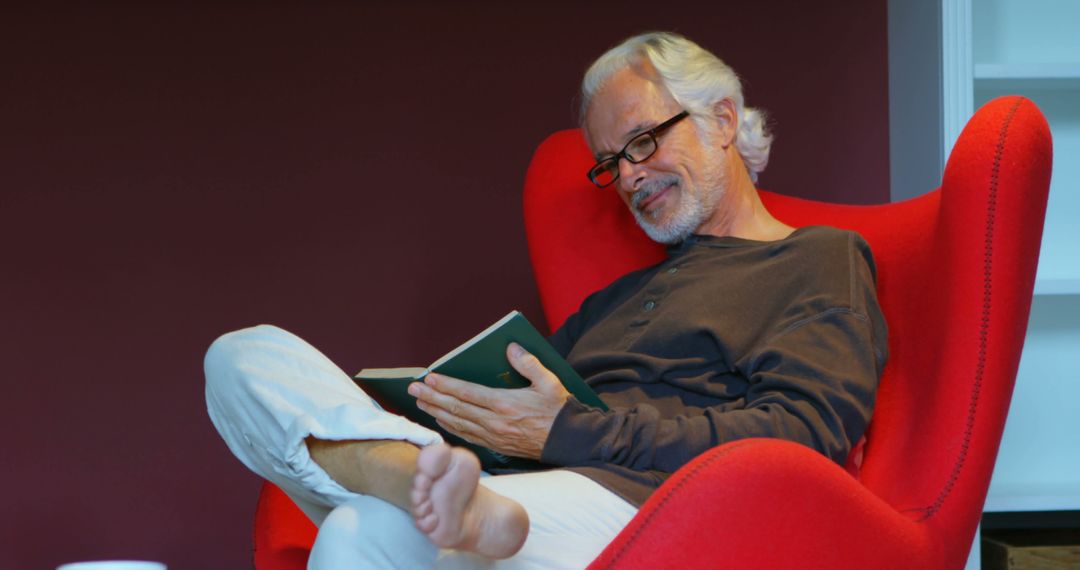 Senior Man Relaxing and Reading at Home in Cozy Chair