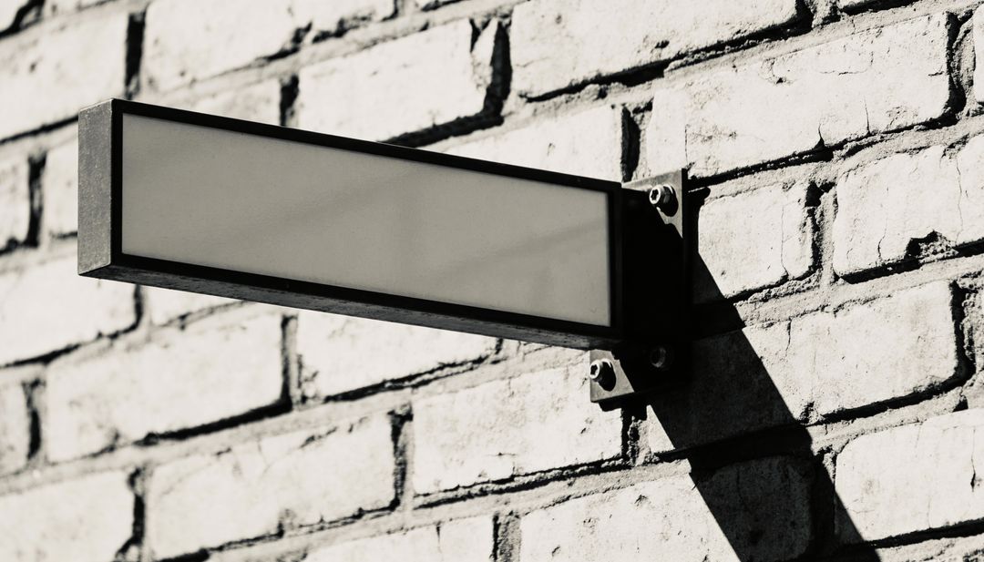 Blank Rectangular Metal Sign Casting Long Shadow on Painted Brick Wall Urban Mockup