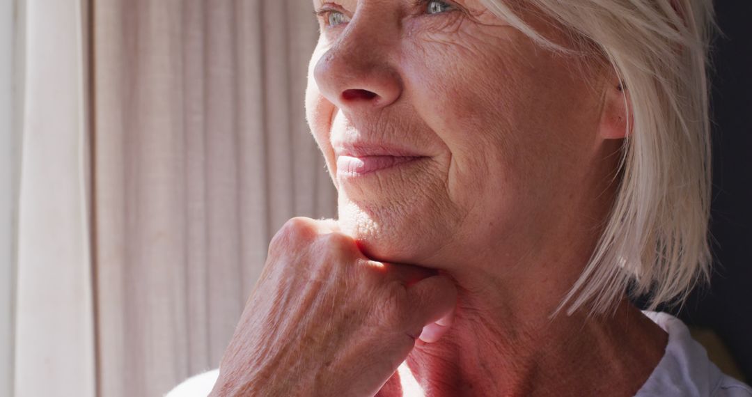 Serene Elderly Woman Contemplating Life Near Sunlit Window - Free Images, Stock Photos and Pictures on Pikwizard.com