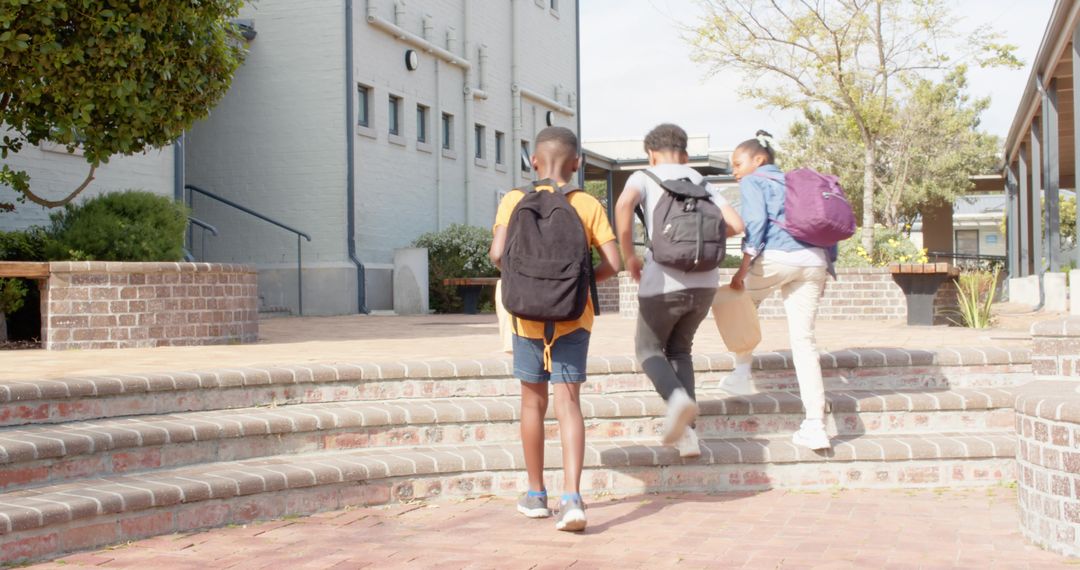 Diverse School Friends Climbing Steps into Courtyard With Backpacks