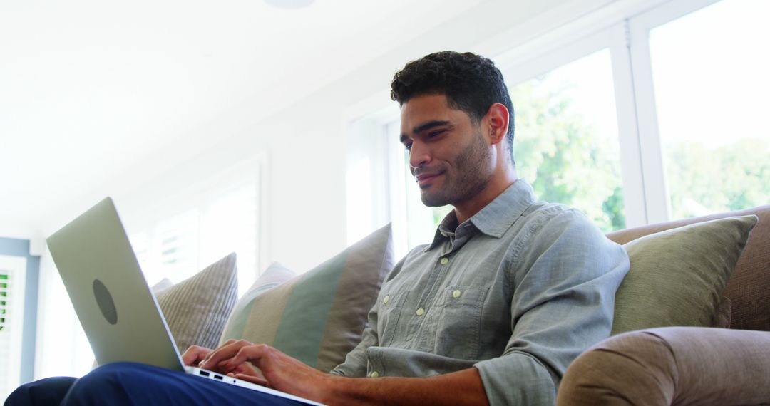 Man Working on Laptop in Bright Living Room - Free Images, Stock Photos and Pictures on Pikwizard.com